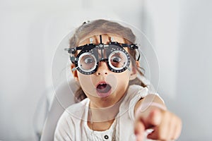 Cute little girl is in ophthalmology clinic with special tool on eyes getting tested