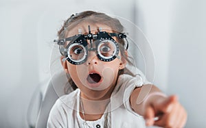 Cute little girl is in ophthalmology clinic with special tool on eyes getting tested