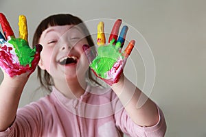 Cute little girl with painted hands. Isolated on gray background