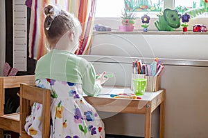 Cute little girl painting in her room at home