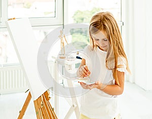 Cute little girl paints on canvas