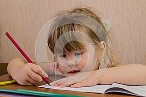 Cute little girl paints and tinkers with colored pencils and scissors