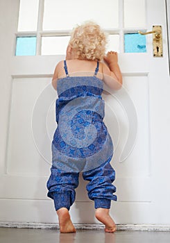 Whens Daddy coming home. A cute little girl peeking out of th front doors window.