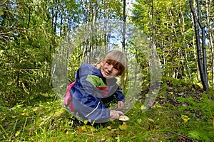 Cute little girl picking mushroom