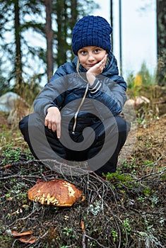 Cute little girl picking mushrooms in autumn forest