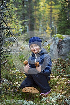 Cute little girl picking mushrooms in autumn forest