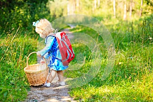 Cute little girl picking mushrooms in forest