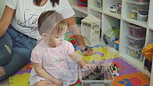Cute Little Girl Picking Up Toys in Plastic Bin