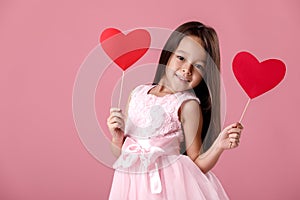 Cute little girl in a pink dress holding a paper heart