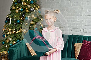 Cute little girl in pink dress with present on background Christmas tree. Merry Christmas and Happy Holidays! Baby healthy and