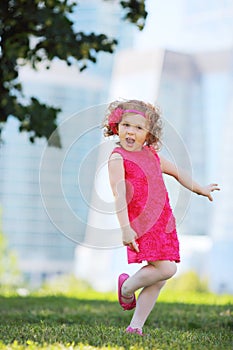 Cute little girl in pink dress stands on one leg