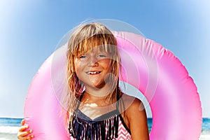 Cute little girl with pink swim ring on the beach