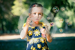 Cute little girl play in park blow soap bubbles