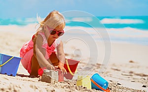 Cute little girl play with sand on beach