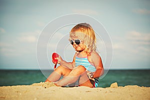 Cute little girl play with sand on beach