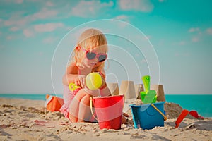 Cute little girl play with sand and toys on beach