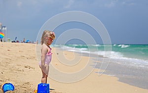 Cute little girl play with sand and water on beach