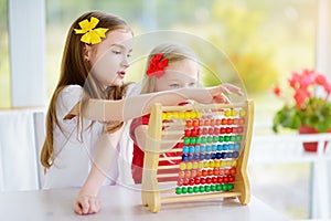 Cute little girl playing with abacus at home. Smart child learning to count.