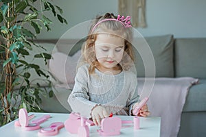 Cute little girl is playing in a beauty salon. Beautiful girl of 3 years old makes makeup with children`s cosmetics at home