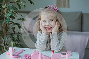 Cute little girl is playing in a beauty salon. Beautiful girl of 3 years old makes makeup with children`s cosmetics at home