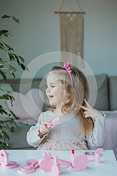 Cute little girl is playing in a beauty salon. Beautiful girl of 3 years old makes makeup with children`s cosmetics at home