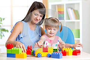 Cute little girl playing block with mother at home