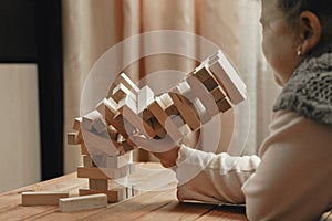 Cute little girl playing board game, building a tower from wooden blocks