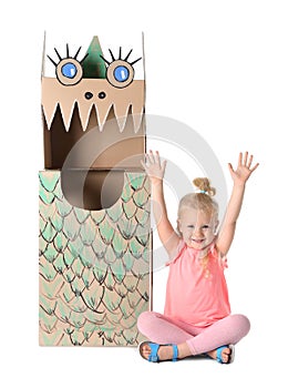 Cute little girl playing with cardboard dragon