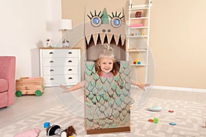 Cute little girl playing with cardboard dragon