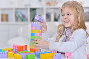Cute little girl playing with colorful plastic blocks