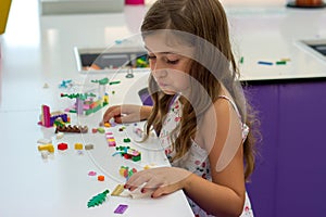 Cute little girl playing with construction toy blocks building a house;  children and toys