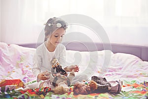 Cute little girl, playing with dolls in bed at home