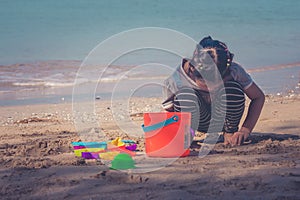 Cute little girl playing and enjoying with colorful beach toys or children toys on sand beach with seascape view in background