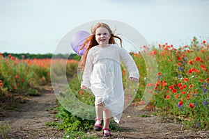 Cute little girl playing in a field with balloon. Summer poppy f