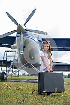 A cute little girl playing on the field by private jet dreaming of becoming a pilot