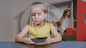 Cute little girl playing games smartphone indoors.