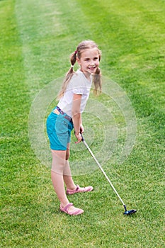 Cute little girl playing golf on a field