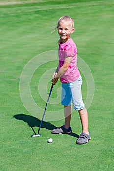 Cute little girl playing golf on a field