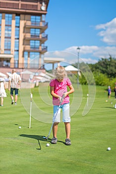 Cute little girl playing golf on a field outdoor