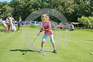 Cute little girl playing golf on a field outdoor