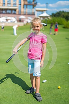 Cute little girl playing golf on a field outdoor