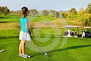 Cute little girl playing golf on a field outdoor