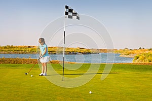 Cute little girl playing golf on a field outdoor