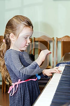 Cute little girl playing grand piano