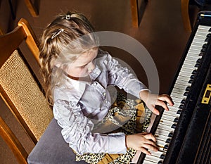 Cute little girl playing grand piano in music school