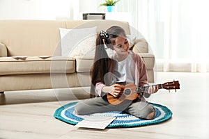 Cute little girl playing guitar on floor