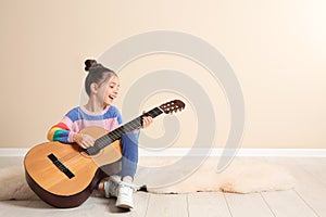 Cute little girl playing guitar on floor in room