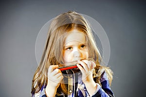 Cute little girl playing harmonica