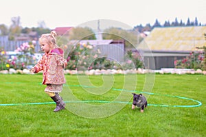 Cute little girl playing with her puppy in the yard