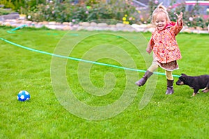 Cute little girl playing with her puppy in the yard